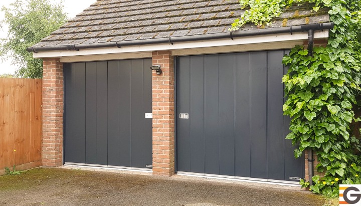 Modern anthracite grey garage doors with brick pillars and lush greenery, providing security and style in East Peckham. Hormann quality.