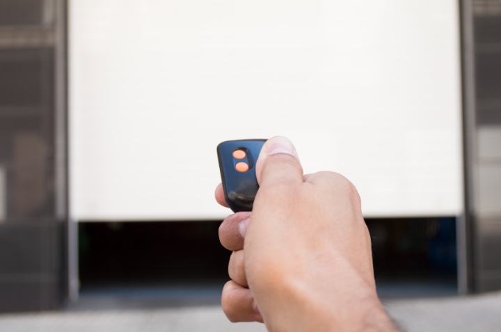 Hand holding a remote control, opening or closing a garage door. Ideal for Southern Doors East Peckham, showcasing convenience and modern access.