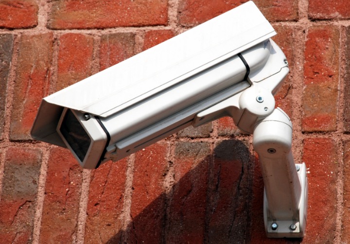 Close-up of a white security camera mounted on a vibrant red brick wall in East Peckham. Enhancing home and business safety.
